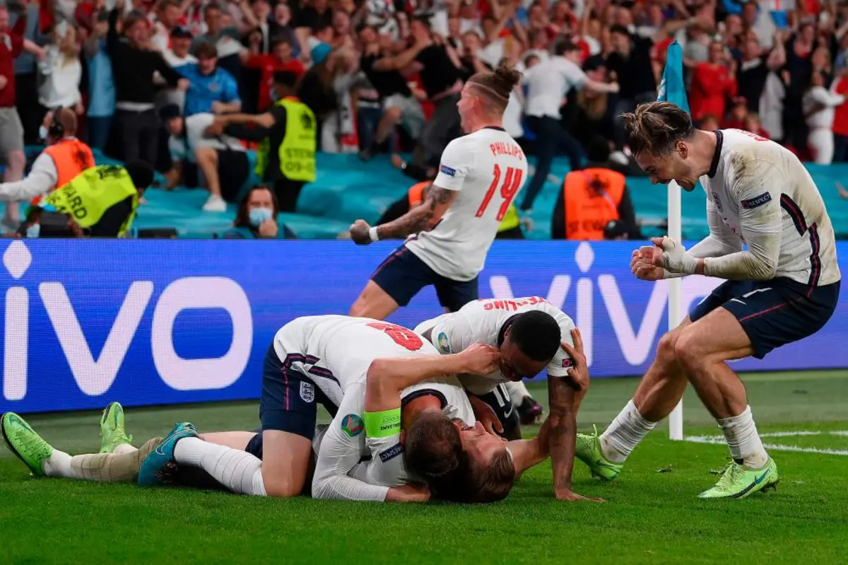 A photo of the England men's national football team celebrating on the field after defeating the Netherlands in the Euro 2024 semi-final. The players are jumping and hugging each other, some with their arms raised in triumph.